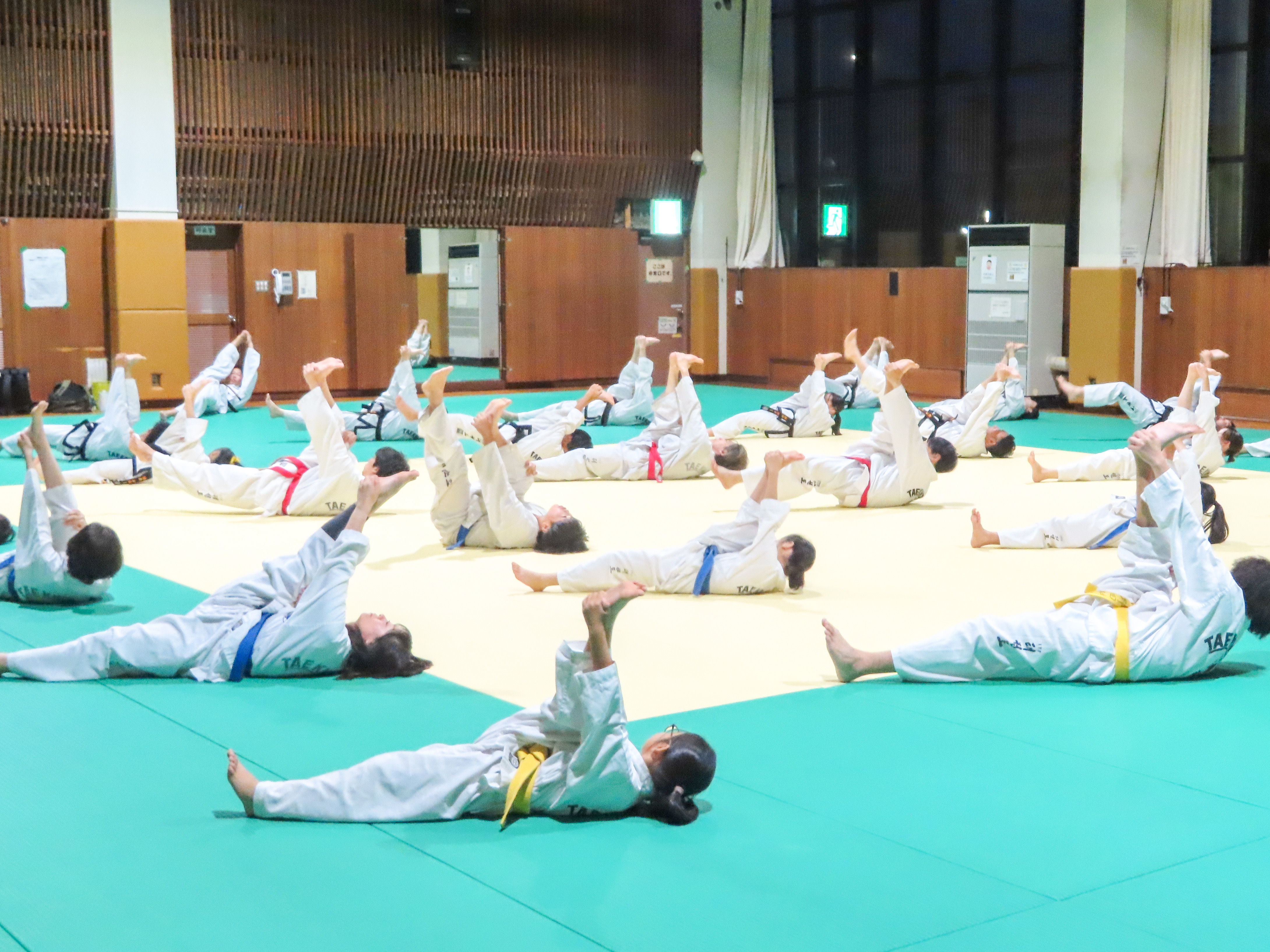 稽古の前に床でストレッチをする稽古生たち