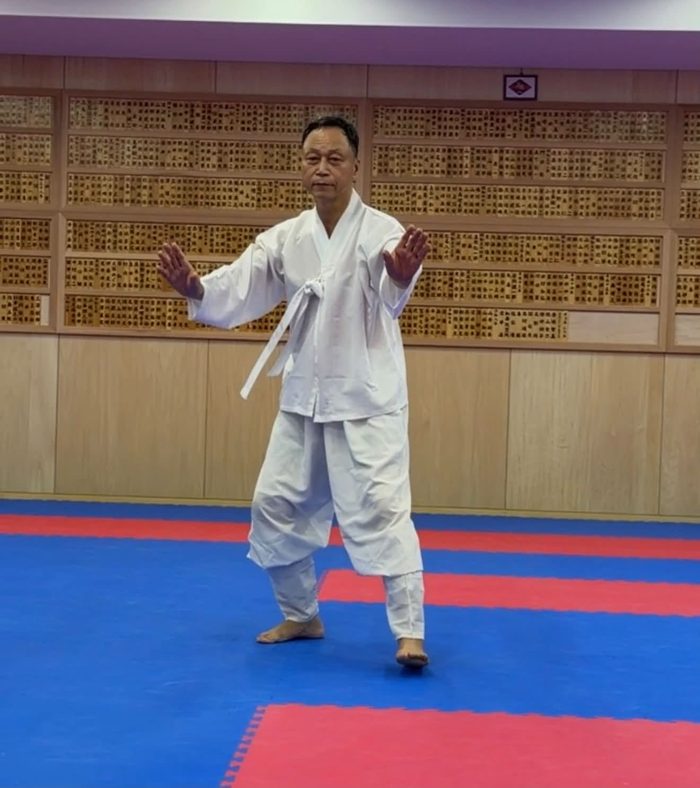 白い道着で棍を手に構える武芸家