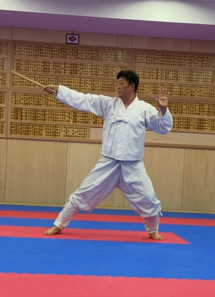 棍を構えて演武する白い道着の武芸家