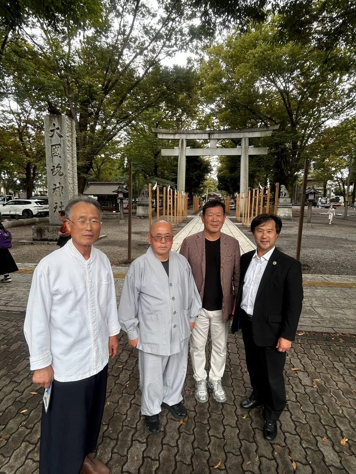 神社の鳥居の前に並ぶ4人