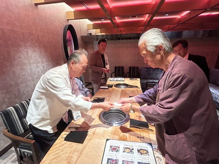 焼肉店の席で挨拶を交わす二人